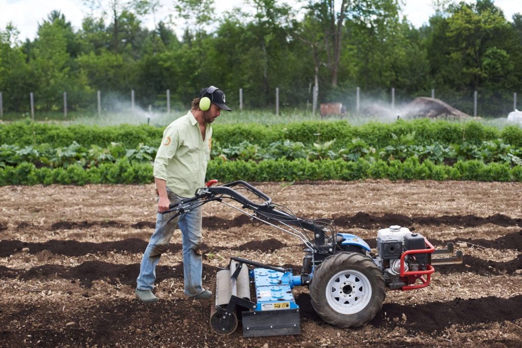 Tractor-mounted agricultural implement working in a field
